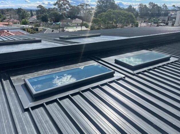 Roofer tracing a leak source around roof penetrations and skylights